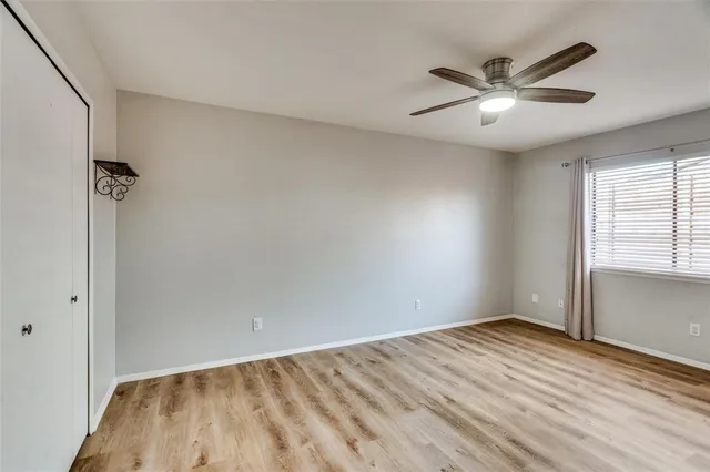 a view of empty room with wooden floor and fan