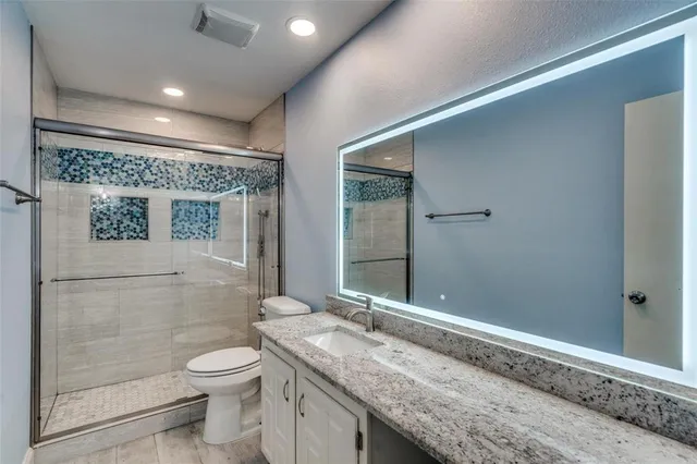 a bathroom with a granite countertop sink a toilet and shower