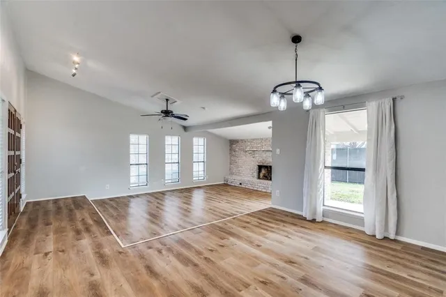 a view of an empty room with window and wooden floor