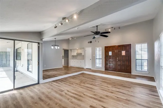 a view of an empty room with window and wooden floor