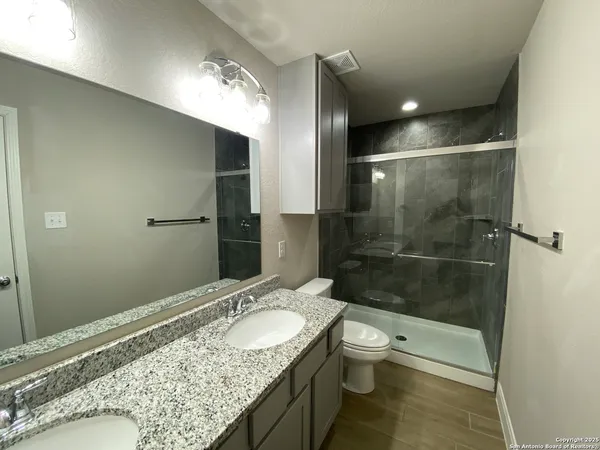 a bathroom with a granite countertop sink a toilet and shower