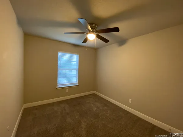 a view of an empty room and window and chandelier fan