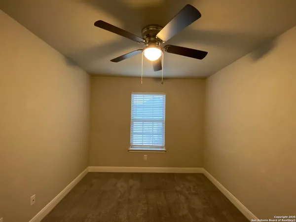 an empty room with a window and a fan