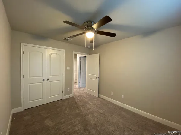 a view of an empty room and chandelier fan