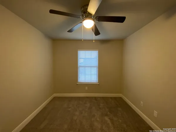 an empty room with a window and a chandelier fan