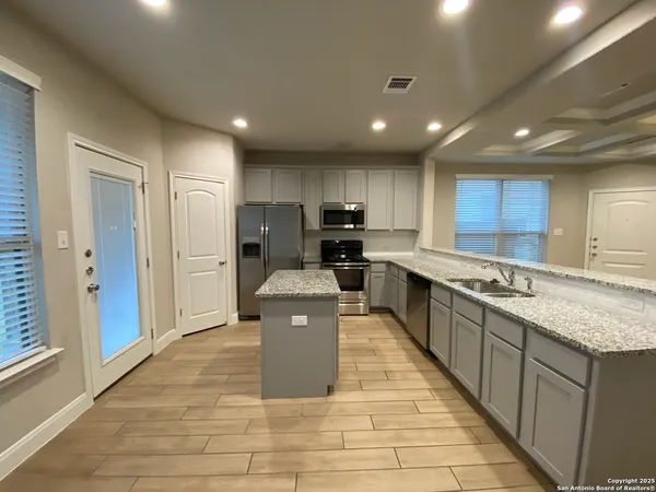 a large kitchen with kitchen island a sink a counter top space stainless steel appliances and cabinets