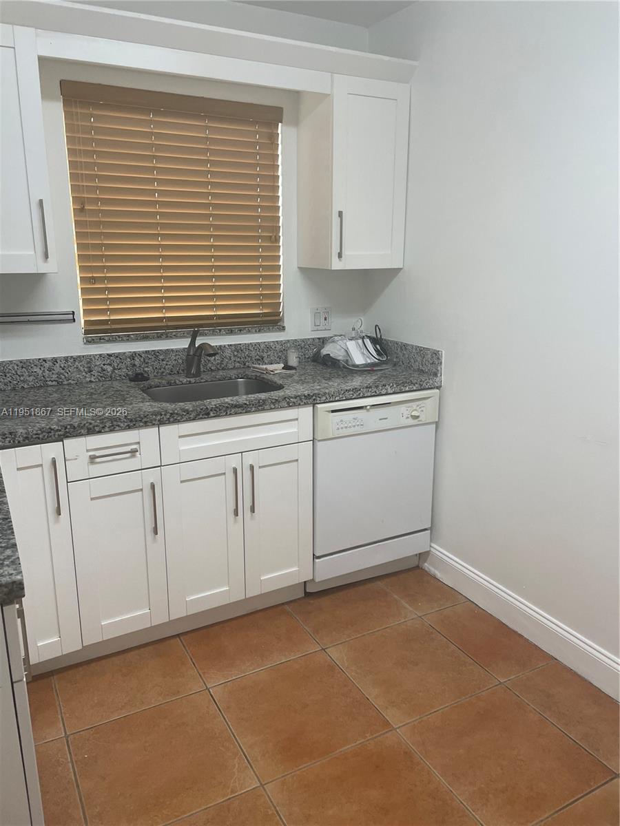 7785 Southwest 86th Street, Unit E123 Miami, FL 33143 - Photo 3 of 8 a kitchen with granite countertop white cabinets and a sink