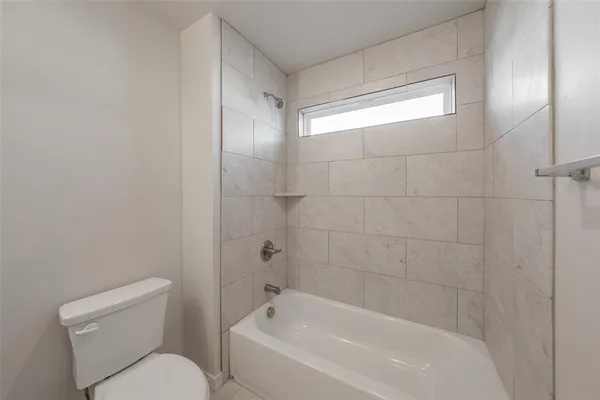 a bathroom with a bathtub shower sink mirror and toilet