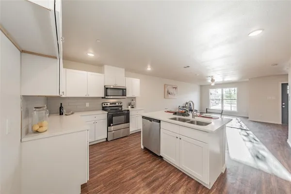 a kitchen with stainless steel appliances a table and chairs in it