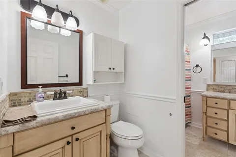 a bathroom with a granite countertop sink mirror vanity and toilet