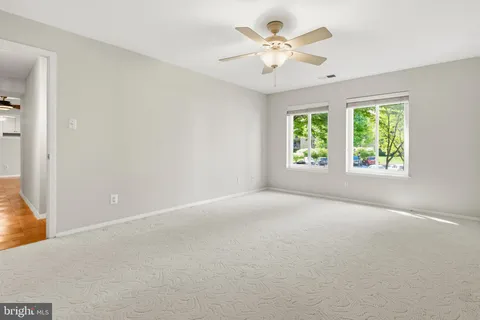 an empty room with chandelier fan and closet area