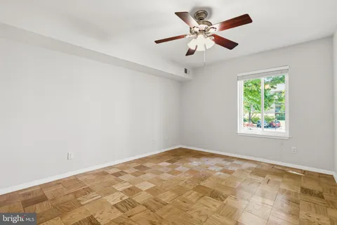 a view of an empty room with window and chandelier fan
