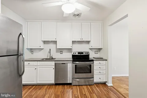 a kitchen with cabinets stainless steel appliances and wooden floor