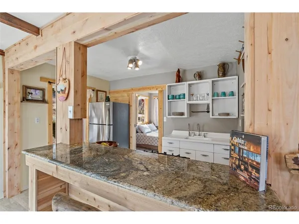 a living room with stainless steel appliances kitchen island granite countertop a refrigerator and cabinets