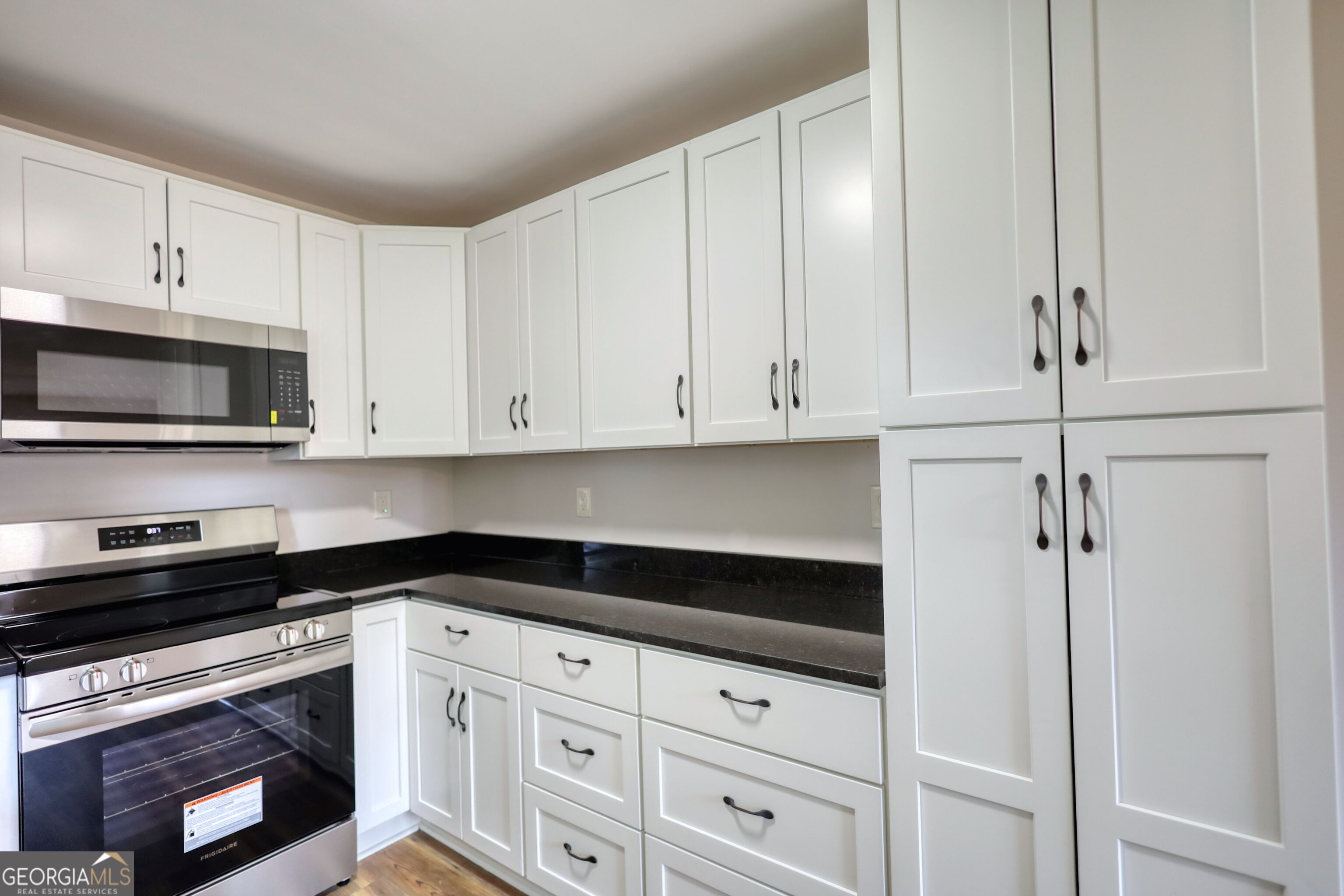 855 Meadow Ridge Drive Madison, GA 30650 - Photo 15 of 41 a kitchen with white cabinets and black appliances
