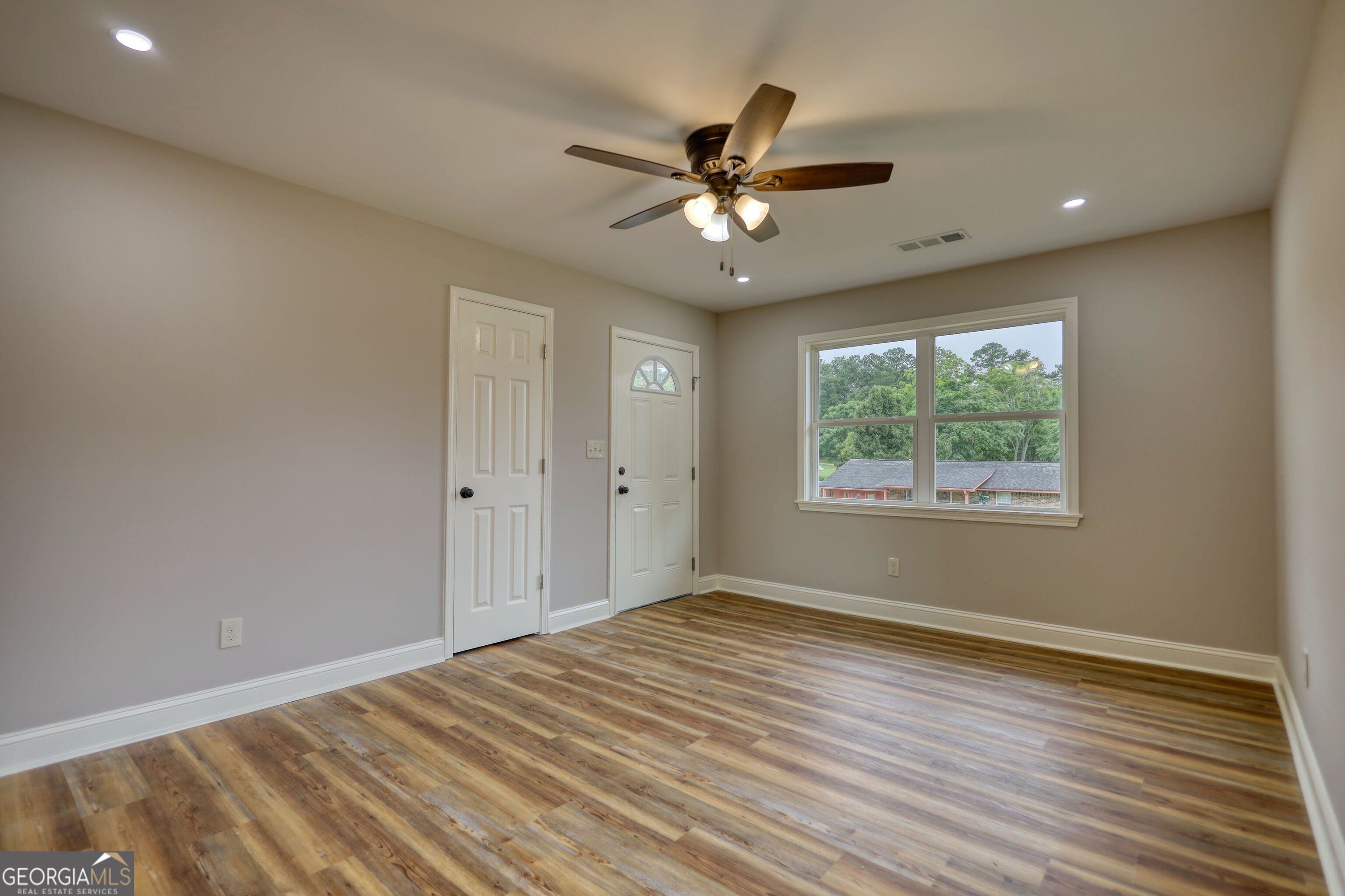 855 Meadow Ridge Drive Madison, GA 30650 - Photo 9 of 41 an empty room with wooden floor fan and windows