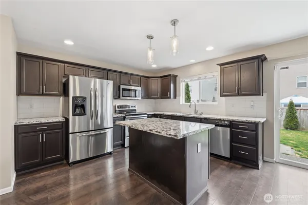 a kitchen with stainless steel appliances granite countertop a refrigerator a stove a sink and a microwave