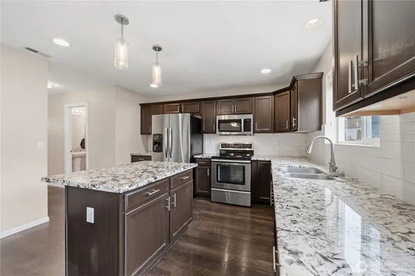 a kitchen with stainless steel appliances granite countertop a sink stove and refrigerator