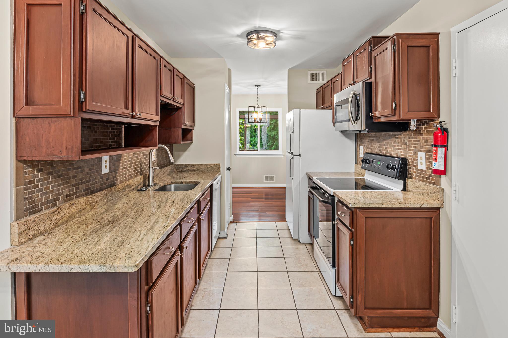 6411 Darwin Road Laurel, MD 20707 - Photo 8 of 41 a kitchen with stainless steel appliances granite countertop a stove top oven a sink a counter space and cabinets