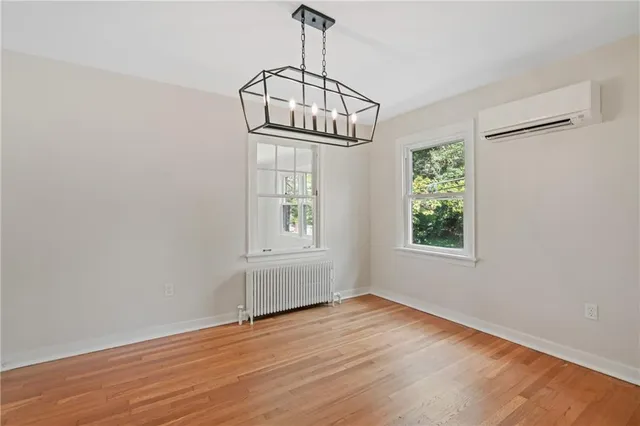 an empty room with wooden floor chandelier and windows
