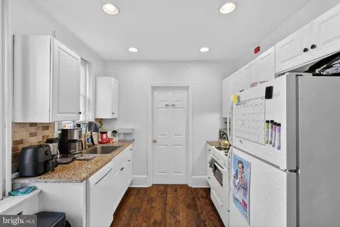 a kitchen with white cabinets and refrigerator