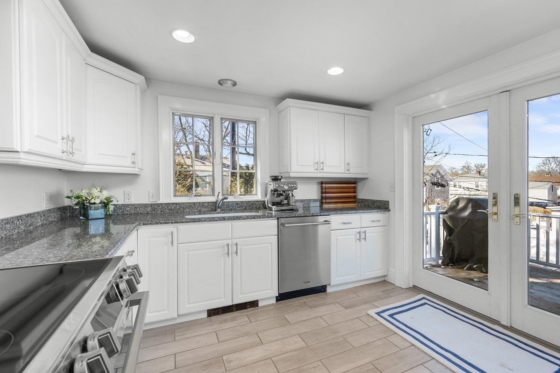 25 Main Street, Unit 3 Marion Center, MA 02738 - Photo 15 of 32 a kitchen with granite countertop white cabinets a sink a window and stainless steel appliances
