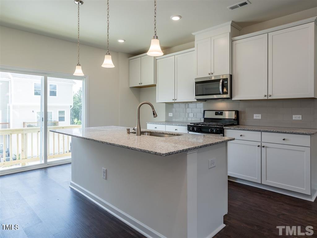 4035 Mahal Avenue Cary, NC 27519 - Photo 6 of 29 a kitchen with stainless steel appliances granite countertop a sink a stove and a wooden floors