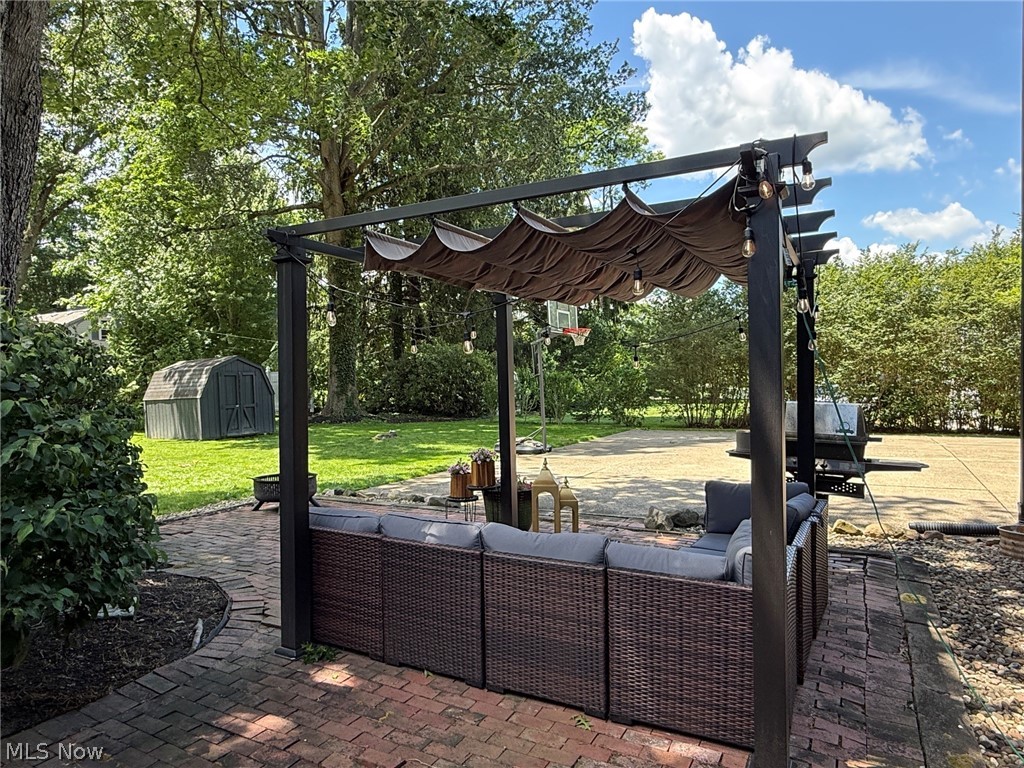 2411 Ridgeview Lane Youngstown, OH 44514 - Photo 42 of 48 Brick paver patio with a black metal pergola featuring a retractable fabric canopy and string lighting