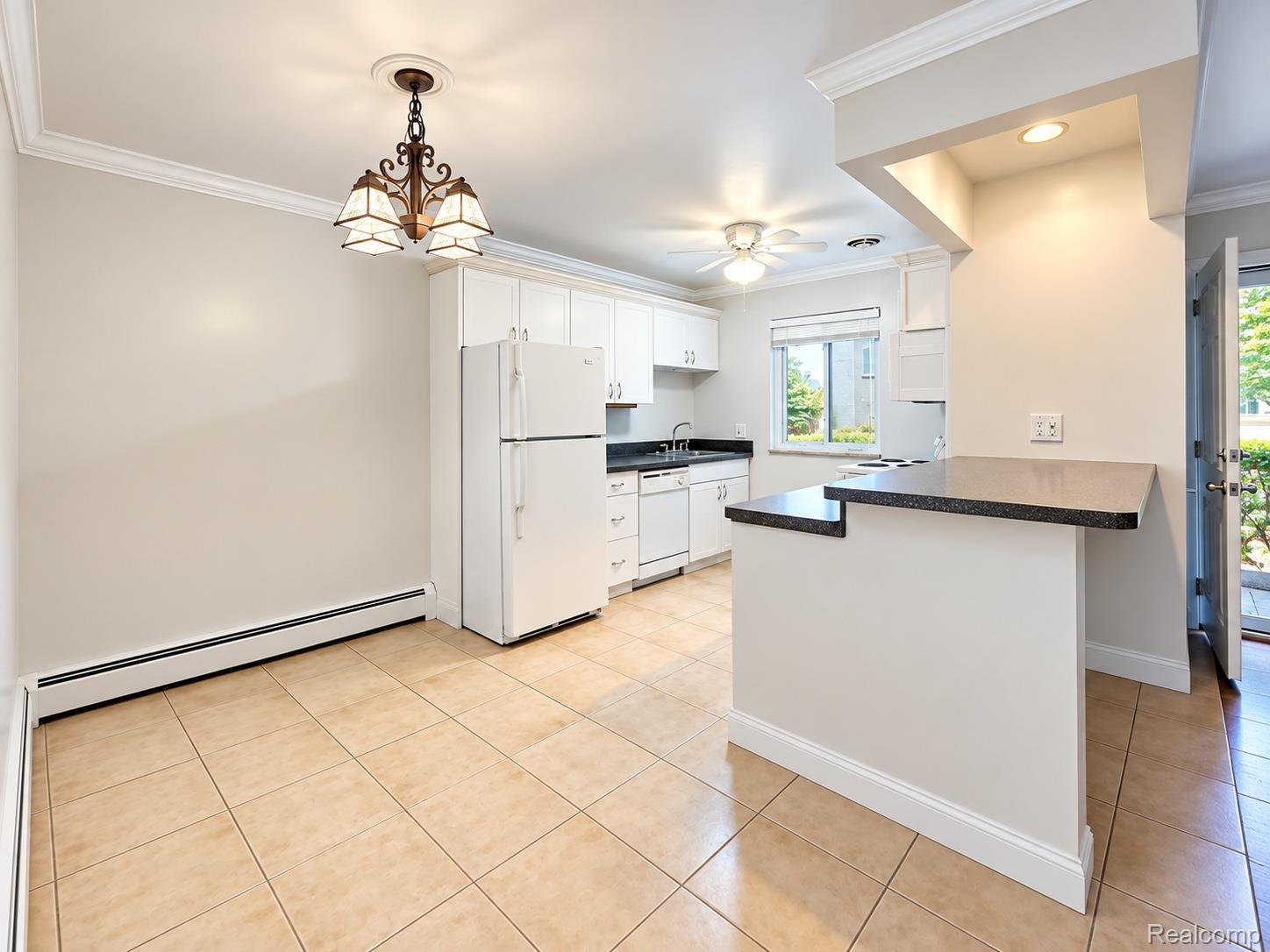 475 South Adams Road, Unit 8 Birmingham, MI 48009 - Photo 5 of 15 Kitchen featuring white cabinetry, dark countertops, a breakfast bar, white appliances, and tiled flooring