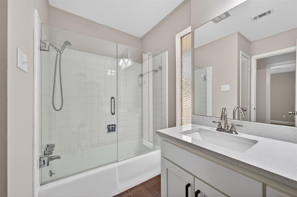 5008 Marble Falls Road Fort Worth, TX 76103 - Photo 20 of 33 a bathroom with a granite countertop sink a mirror a bathtub and shower