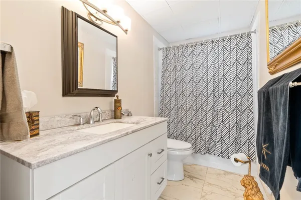 a bathroom with a granite countertop sink toilet and mirror