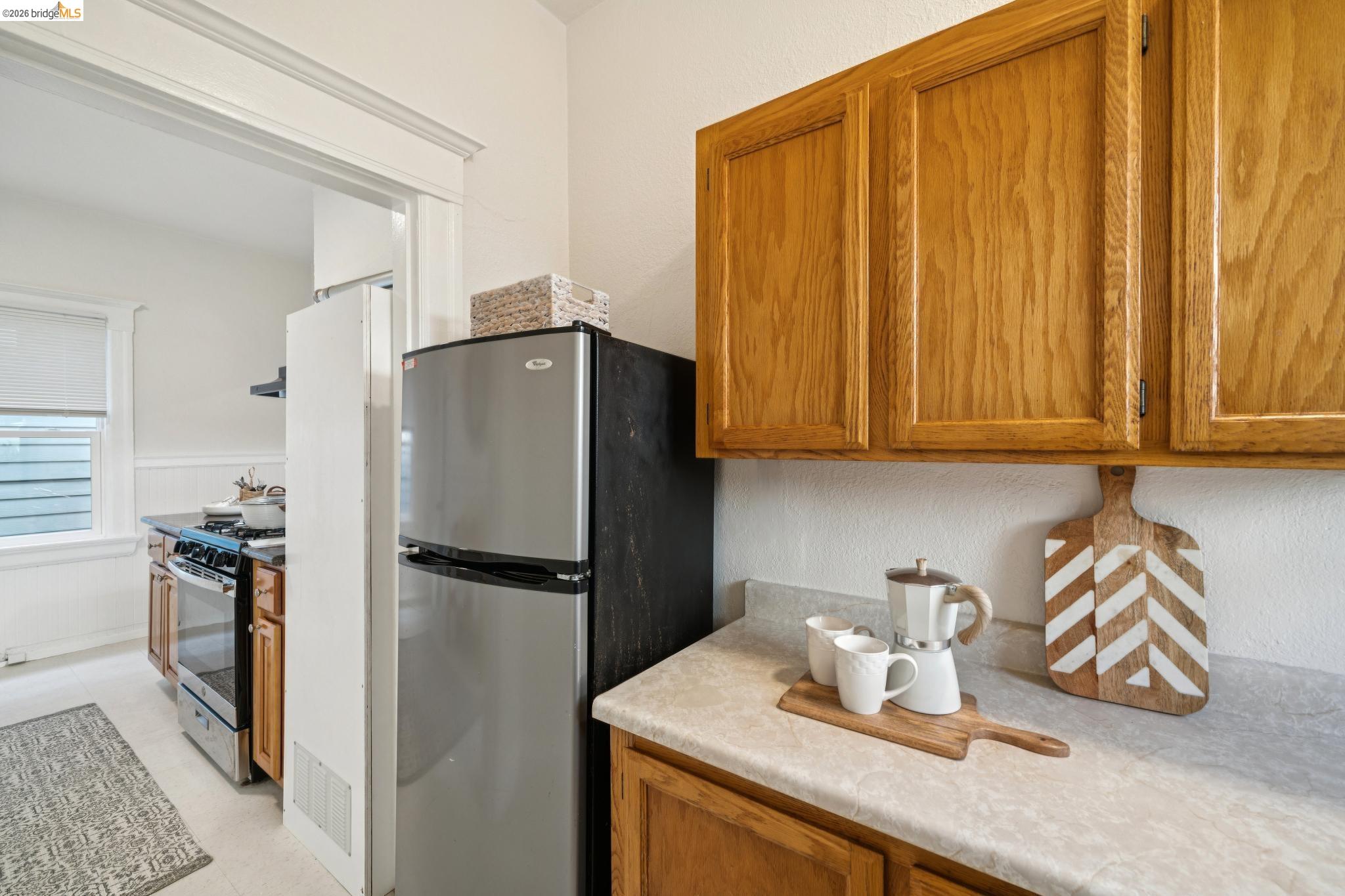 2923 Wheeler Street Berkeley, CA 94705 - Photo 7 of 28 Kitchen with wood finish cabinets, stainless steel appliances, light countertops, wainscoting, and a textured wall