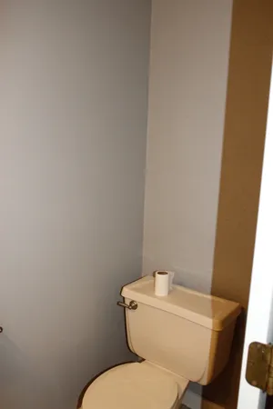 a white toilet sitting next to a white wall