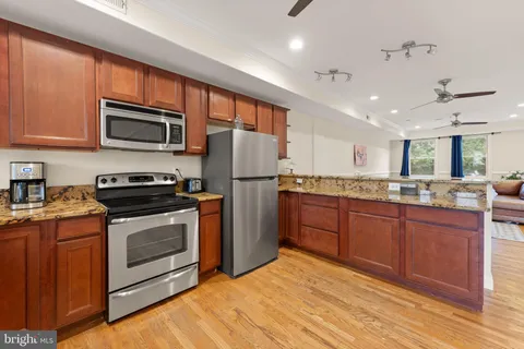 a kitchen with stainless steel appliances granite countertop a stove a sink dishwasher a refrigerator and a microwave oven with cabinets