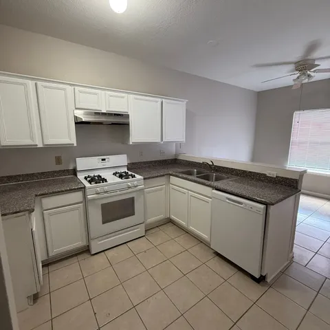 a white kitchen with granite countertop a sink and a stove