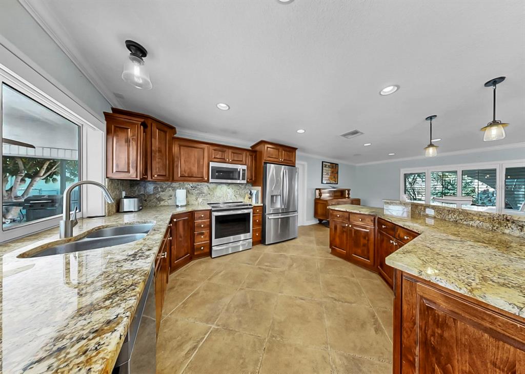 6317 Cocoa Lane Apollo Beach, FL 33572 - Photo 19 of 63 a kitchen with stainless steel appliances granite countertop a stove top oven a sink dishwasher a dining table and chairs with wooden floor