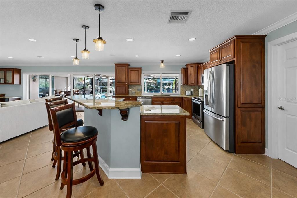 6317 Cocoa Lane Apollo Beach, FL 33572 - Photo 22 of 63 a kitchen with stainless steel appliances granite countertop a refrigerator a stove a sink a dining table and chairs with wooden floor