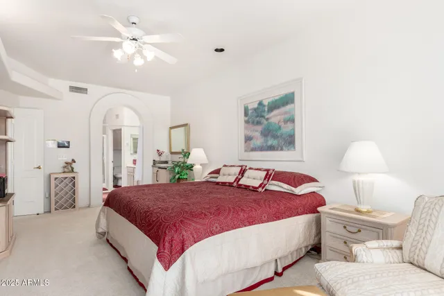 a spacious bedroom with a bed a flat screen tv and a dresser