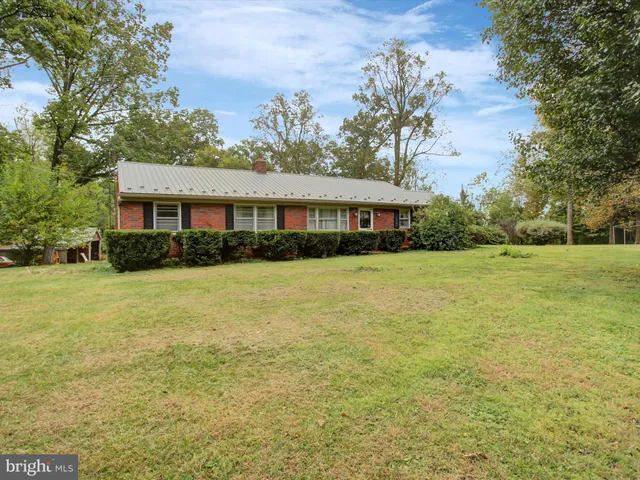 a view of house with yard outdoor seating and covered with trees