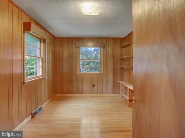a view of an empty room with wooden floor and a balcony