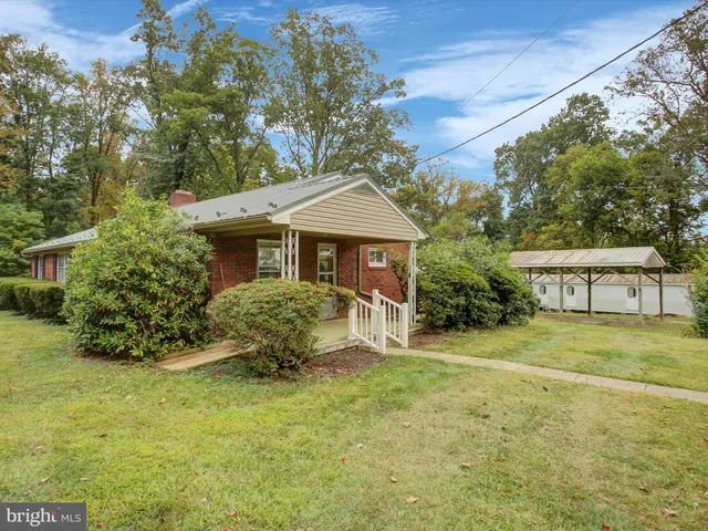a backyard of a house with table and chairs under an umbrella