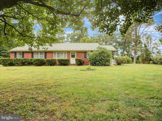 a view of house with yard outdoor seating and covered with trees