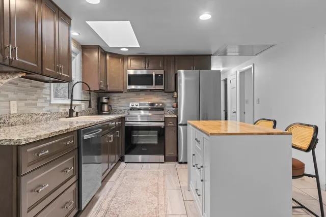 a kitchen with stainless steel appliances granite countertop a refrigerator stove microwave and sink