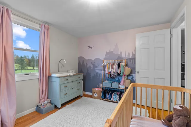 a view of a bedroom with baby crib and a window