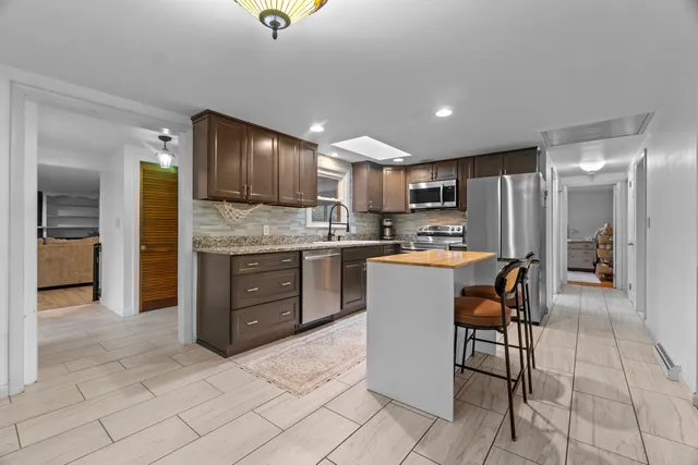 a kitchen with kitchen island granite countertop wooden cabinets a sink a stove a oven and a refrigerator