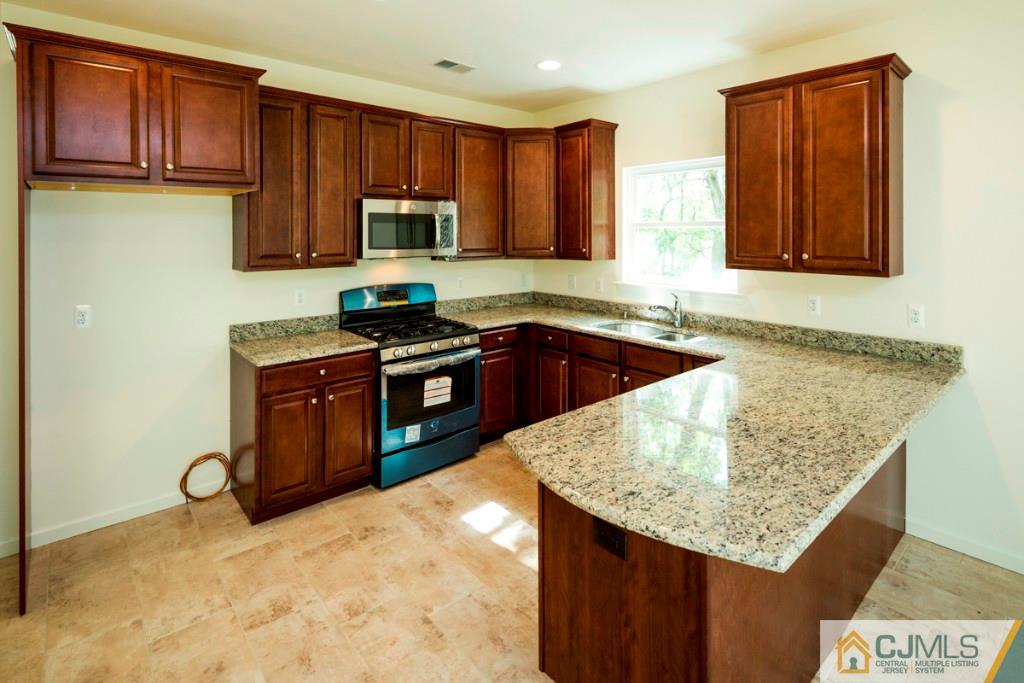 388 Aldrich Road Howell, NJ 07731 - Photo 6 of 24 a kitchen with granite countertop a sink a stove and a wooden cabinets