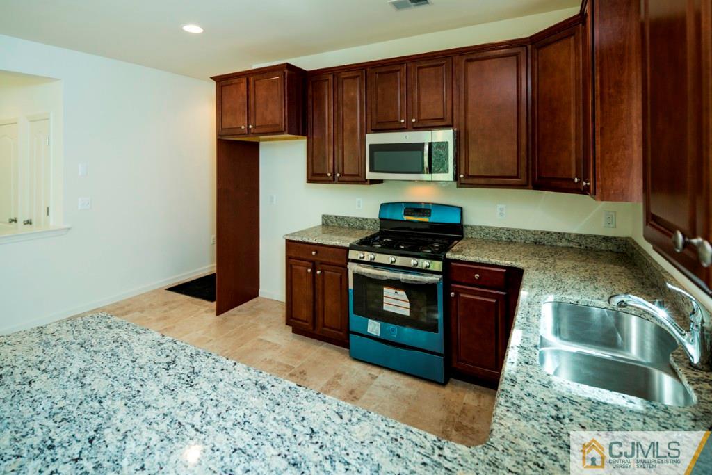 388 Aldrich Road Howell, NJ 07731 - Photo 10 of 24 a kitchen with stainless steel appliances granite countertop a stove a sink and a microwave