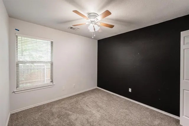 an empty room with a ceiling fan and a window
