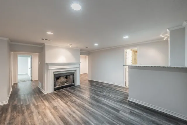 a view of an empty room with wooden floor fireplace and a window