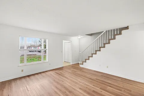 a view of an empty room with wooden floor and windows